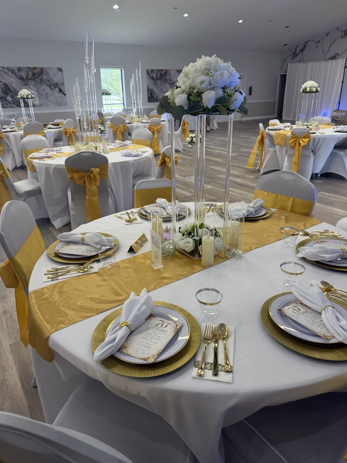 Gold chargers and white floral centerpieces on a dressed reception table