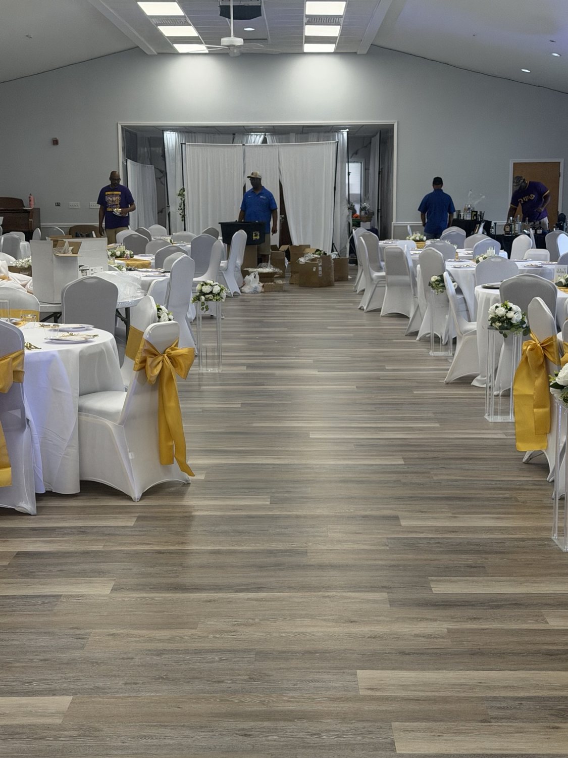 Wide view of an event room arranged with white and gold table décor