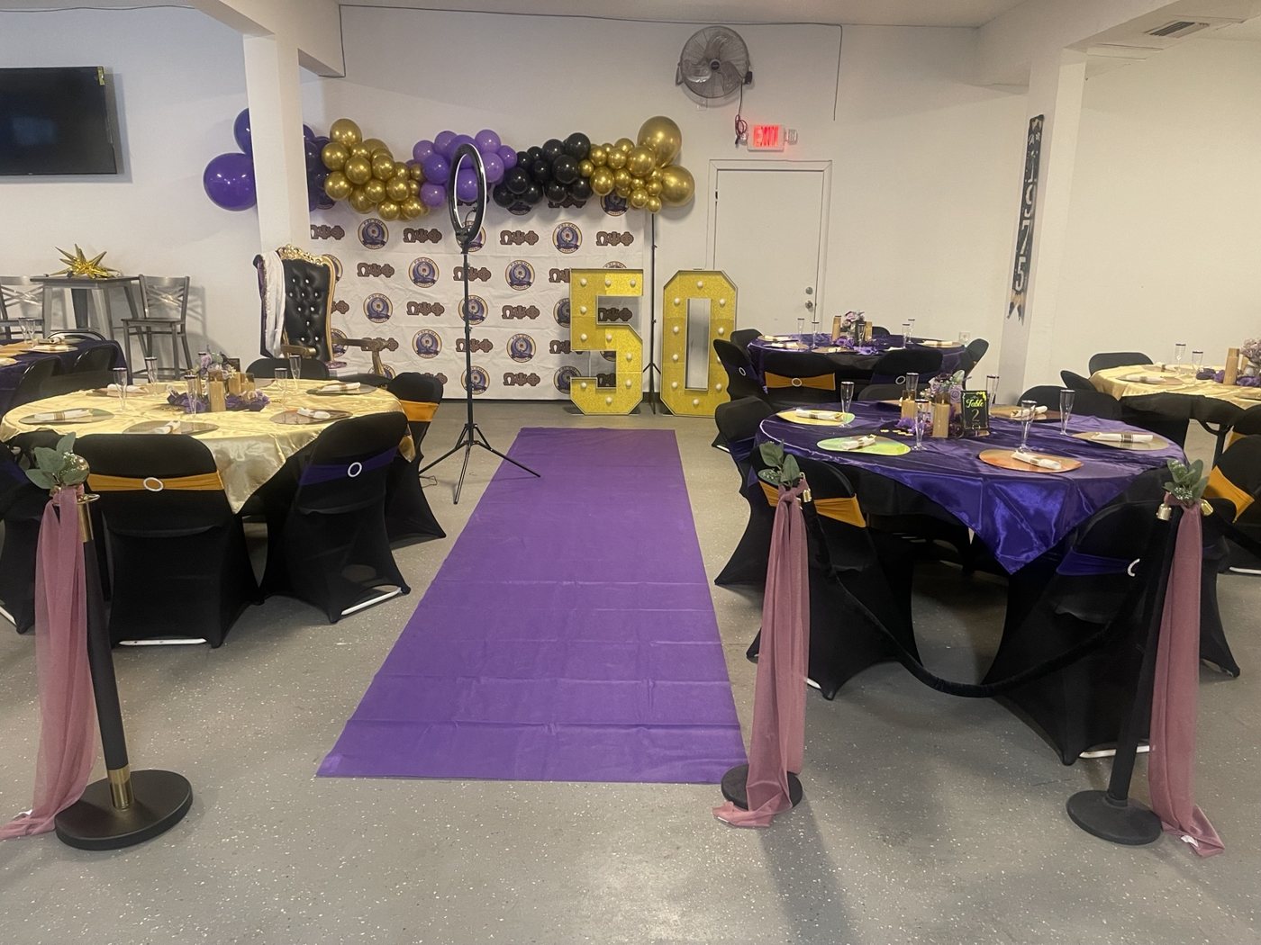Purple carpet leading to a purple, gold, and black milestone celebration setup