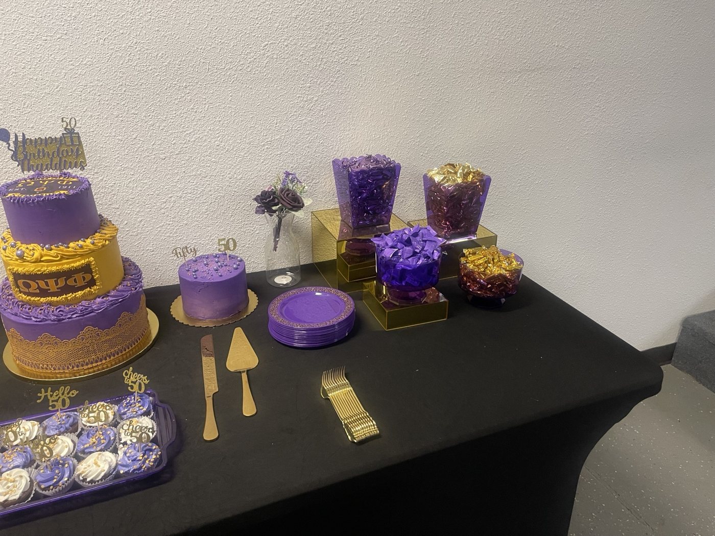 Close view of a purple and gold birthday dessert-table arrangement