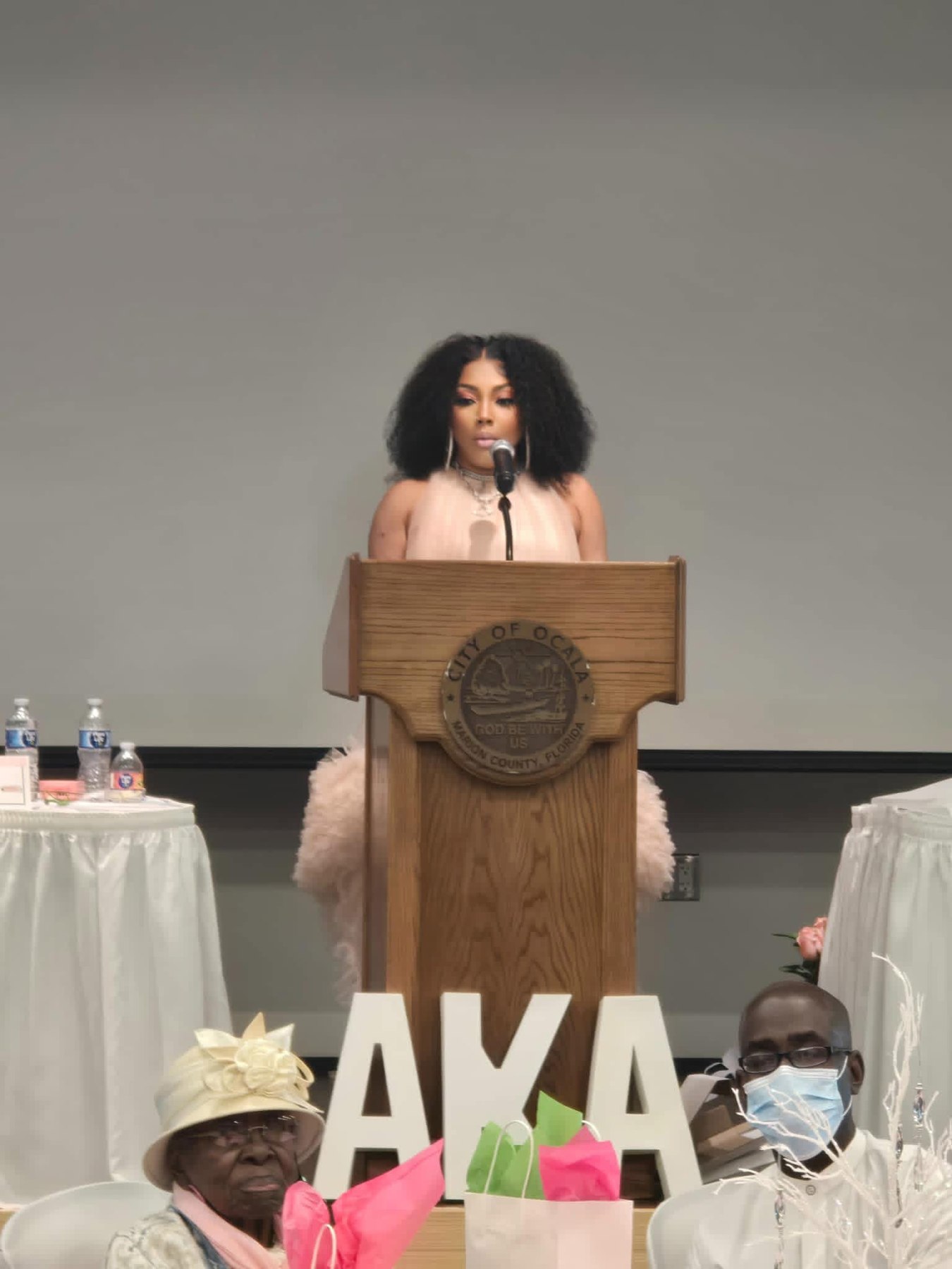Tasha J. Neasman speaking at a podium during an event